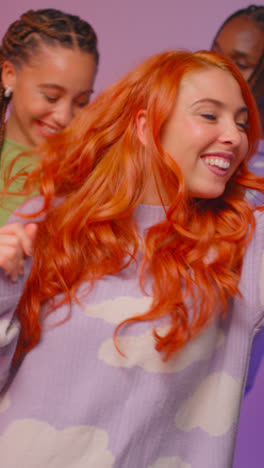 Vertical-Video-Studio-Shot-Of-Smiling-Gen-Z-Friends-Dancing-At-Party-Against-Pink-Background